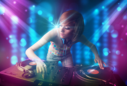 Dj girl mixing music in a club with blue and purple lights