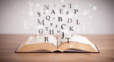 Opened book with flying letters