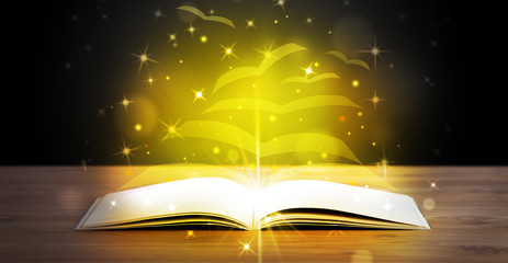 Open book with golden glow flying paper pages