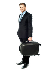 Happy young business man holding suitcase