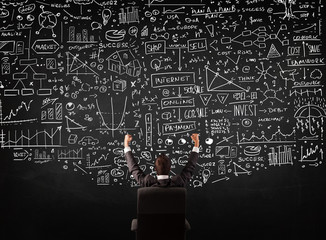 Businessman sitting in front of a blackboard with charts