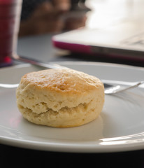 Scone on a white plate and laptop computer