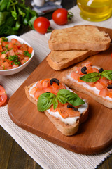 Delicious bruschetta with tomatoes on cutting board close-up