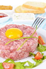 Delicious steak tartare with yolk on plate on table close-up