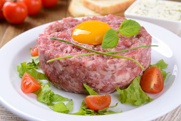 Delicious steak tartare with yolk on plate on table close-up