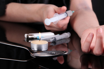 Drug addict with syringe in action on black background