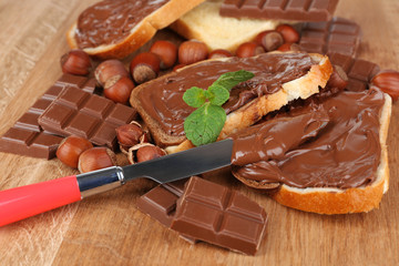 Bread with sweet chocolate hazelnut spread on wooden background