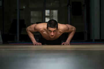 Fototapeta na wymiar Young Man Doing Press Ups In Gym