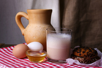 Eggnog with milk and eggs on table and fabric background