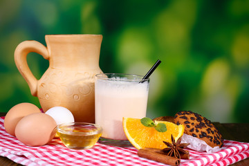 Eggnog with milk and eggs on tablecloth on natural background