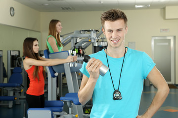 Young trainer and womans engaged in simulator in gym
