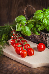 Ripe cherry tomatoes and fresh herbs on wood