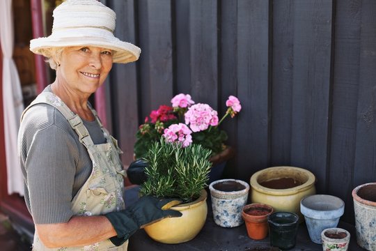 Senior Woman Planting Flowers In A Pot