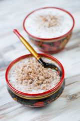 Boiled buckwheat with milk served in khokhloma tableware
