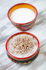 Buckwheat with milk, wooden background, vertical shot