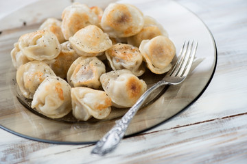 Glass plate with fried pelmeni, close-up