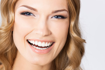 Young cheerful smiling woman, on gray