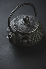 Obraz na płótnie Canvas Close-up of a black cast-iron asian teapot, vertical shot