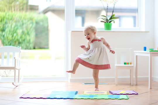 Happy blonde toddler girl having fun dancing indoors
