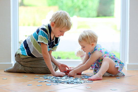 toddler girl playing puzzles with her teenager brother