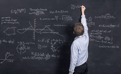 High IQ. Smart kid doing complex math on black chalkboard
