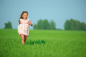 Young happy girl running at green wheat field