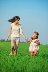 Young happy girls running at green wheat field
