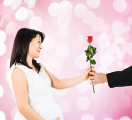 Male hand giving a red rose flower to a pregnant woman,Unrecognizable man.