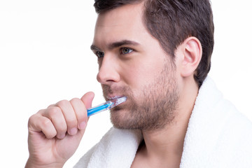 Happy young man brushing teeth.