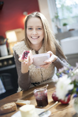 cheerful young woman at breakfast in her kitchen