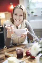 cheerful young woman at breakfast in her kitchen