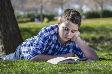 Young boy reading a book in the woods with shallow depth of fiel