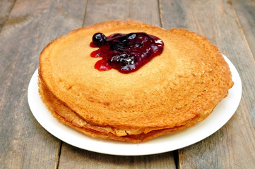 pancakes with jam on a plate on a wooden table