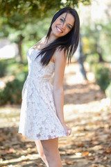 Fototapeta premium Young woman wearing white dress in urban park
