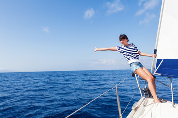 Happy woman on the bow of a Sail Boat with arm raised. Copy space