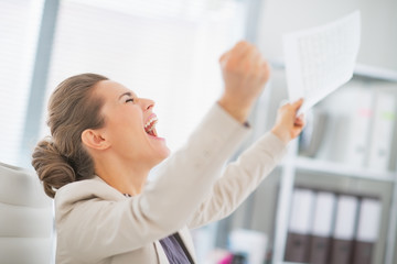 Happy business woman in office rejoicing success
