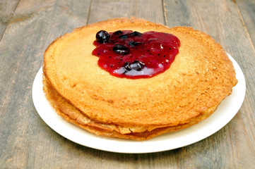 pancakes with jam on a plate on a wooden table