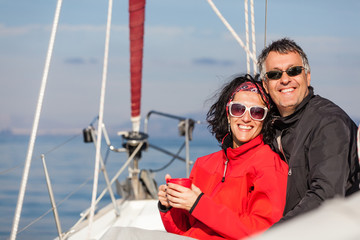 Mature heterosexual couple enjoying on the bow of a Sail boat