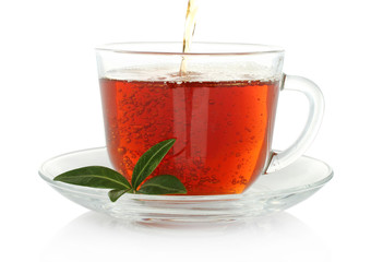 Tea pouring into cup with green leaves on a white background .