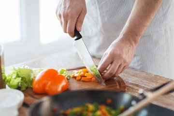 close up of male hand cutting pepper on board