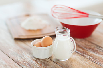 jugful of milk, eggs in a bowl and flour