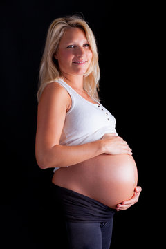 Pregnant woman touching her belly with hands. Isolated over a bl