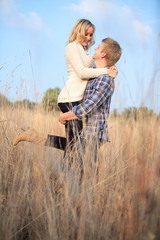 Young adult man holding his girlfriend up