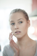 closeup of a beautiful young woman looking herself in a mirror