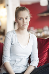 portrait of a beautiful young woman sit on a red couch