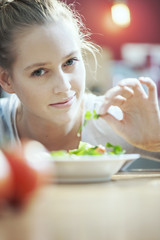 Young woman in her kitchen holding an aromatic herb for her sala