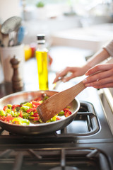 Closeup on hands stirring vegetables in a pan