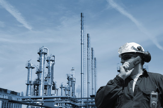 industry worker in front of large oil and gas refinery