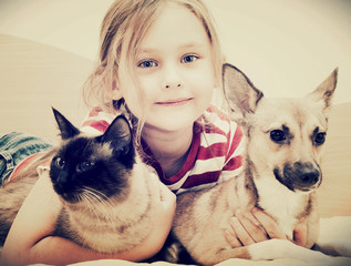 child hugging a cat and dog