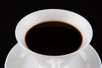 Coffee in a white cup over black background